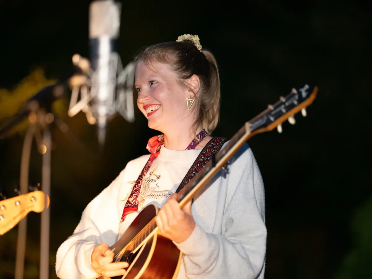 Henja mit Gitarre bei einem Auftritt im Abendlicht